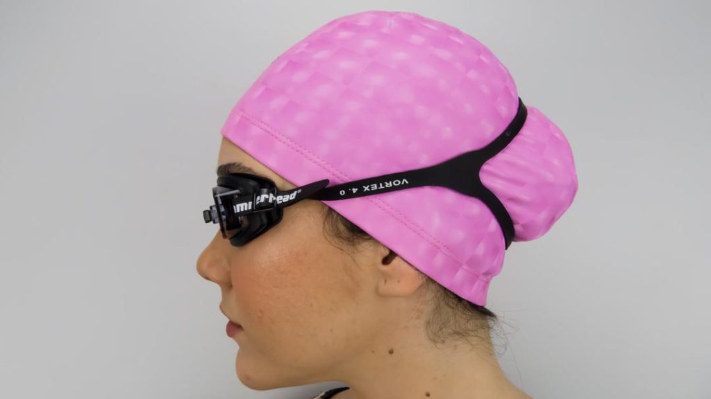 Mulher usando óculos de natação e touca rosa